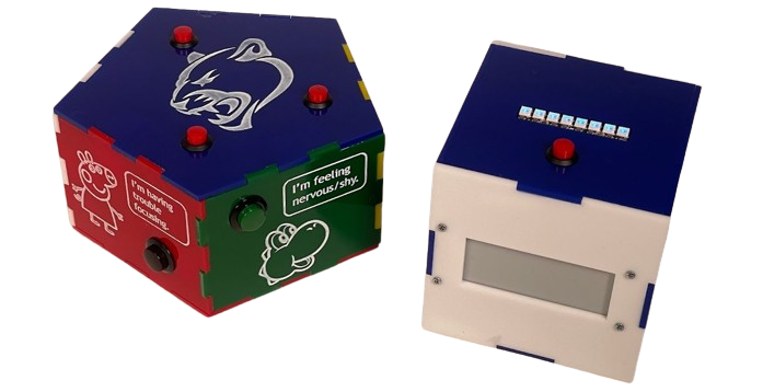 Two multicolored plastic enclosures side by side. On the left, the enclosure has a pentagonal blue lid with the Penn State panther logo on it, and a green and red side facing the viewer, with different white cartoons and text boxes on them, and pushbuttons. The box on the right is a cube with a row of blue illuminated LEDs on the top and a red pushbutton, as well as a blank white screen facing us.