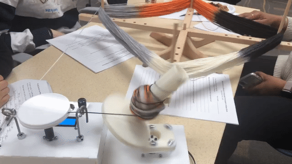 Moving image showing a motorized electronic device winding a ball of yarn from a multicolored skein.
