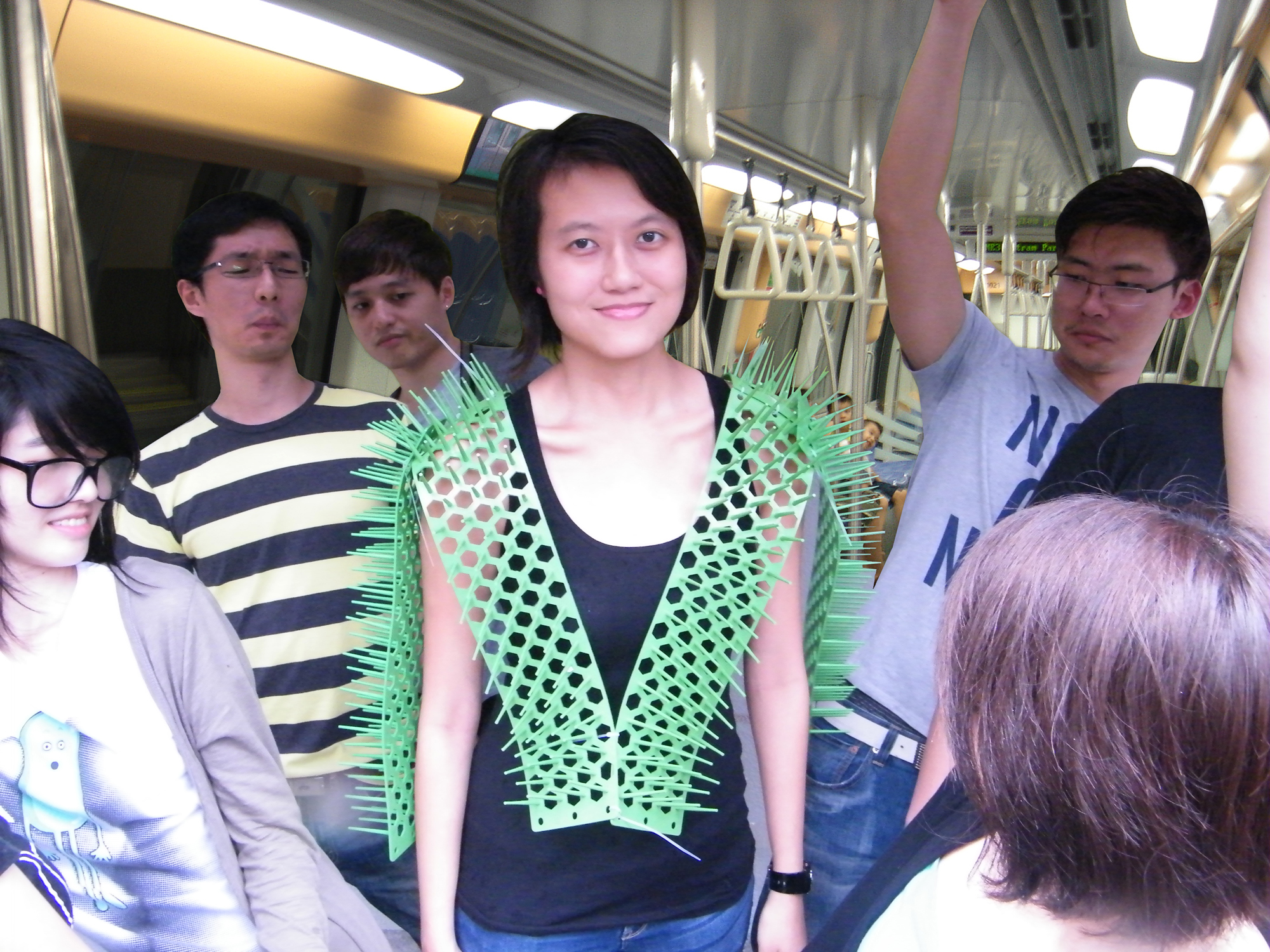 Image of young woman on a subway wearing several strips of plastic spikes across her chest and back; they protrude perhaps 5" off of her body. A group of people around her keep their distance and make grimacing expressions.