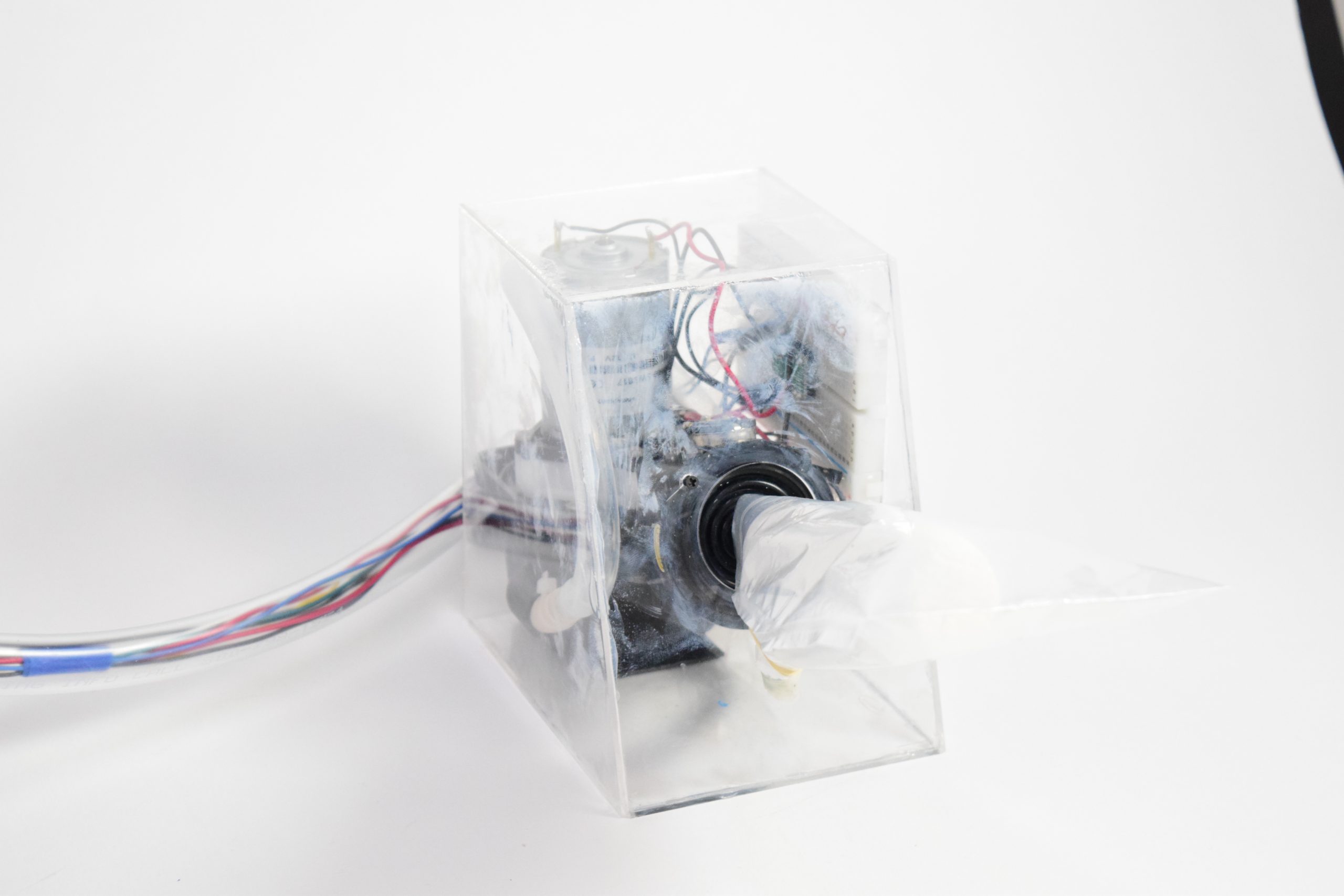 This picture shows an acrylic box with an air pump and wires inside. There is a clear tube with wires and a joystick attached to the box.