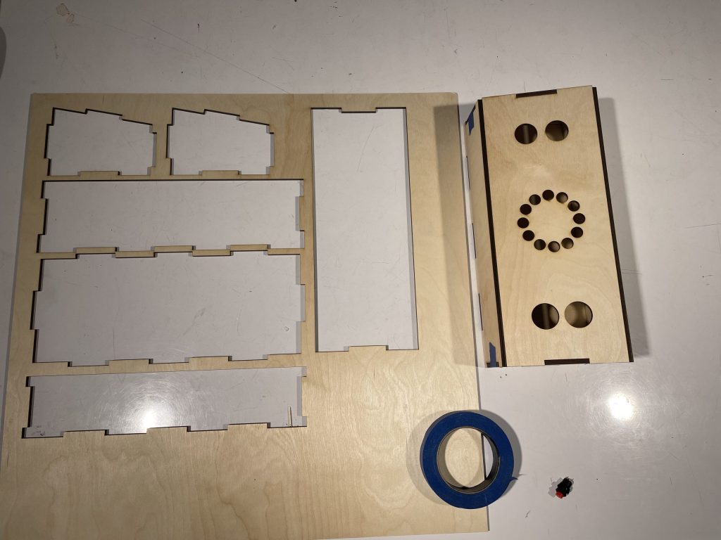 On the left is a piece of plywood with parts cut out of it. The parts were used to make a finger joint box that is on the right of the plywood