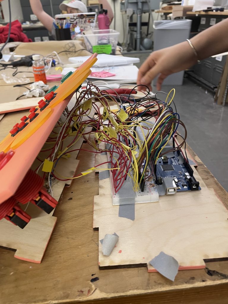 All wires, buttons, and breadboards are placed into pieces of plywood that are attached together with tape