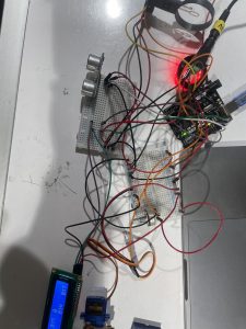 A breadbord with a servo, ultrasonic ranger, LCD, wind sensor, and NEOPIXEL LED wired in. Wires are very tangled