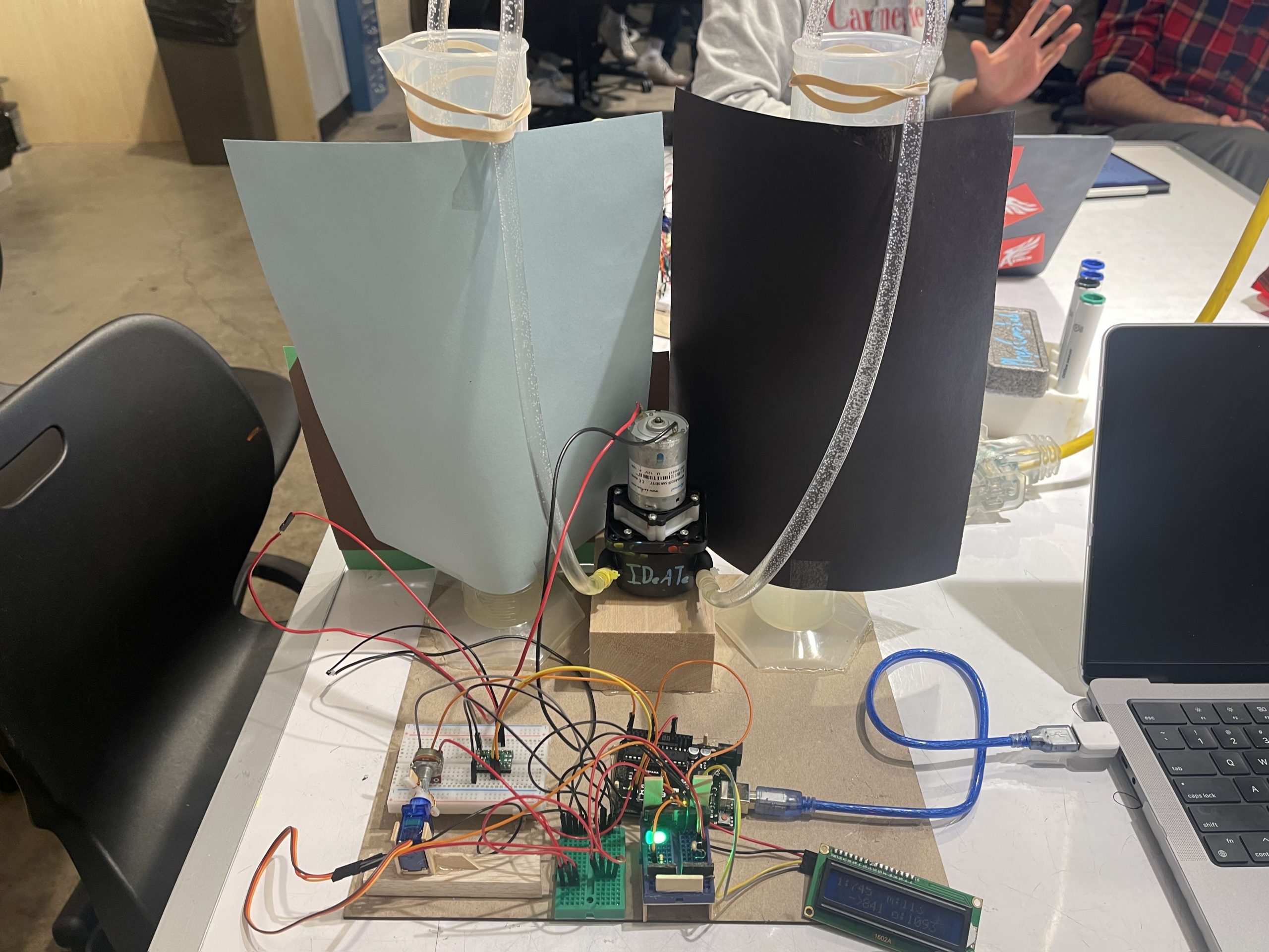 Top level view of project showing Arduino, transparency station, servo motor, potentiometer, peristaltic pump, and two graduated cylinders filled with water.