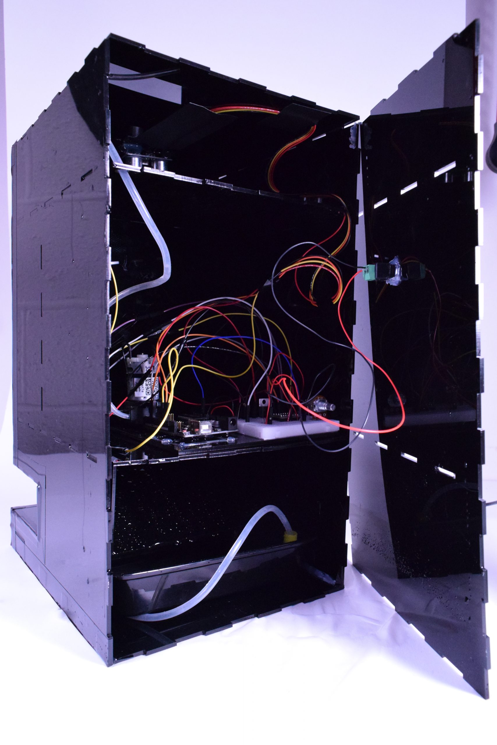 Back view of the fountain box with back panel hinged open, revealing circuits, tubes, and water containers inside.