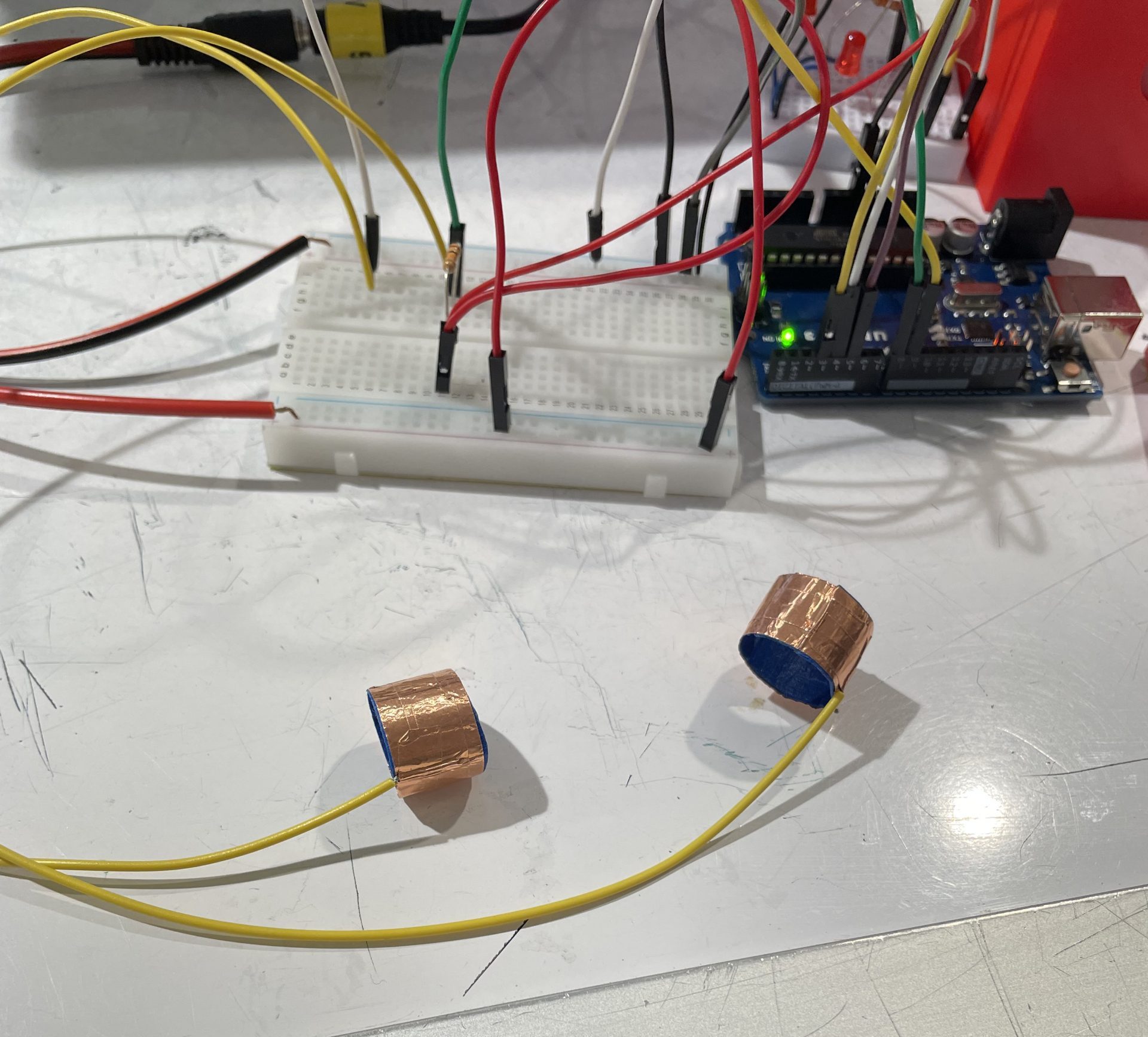 two rings made of copper take attached to wires attached to a switch layout on a breadboard