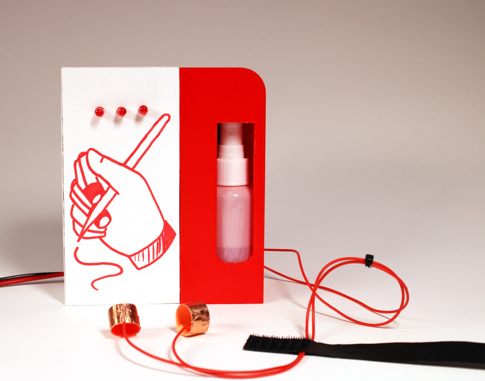 A 8" tall by 4" wide box, with a red hand-drawing of a hand holding a pen on the front of it, and three red LEDs above the drawing. There is a small plastic bottle visible inside the device through a window, and two copper loops on cords in the foreground.