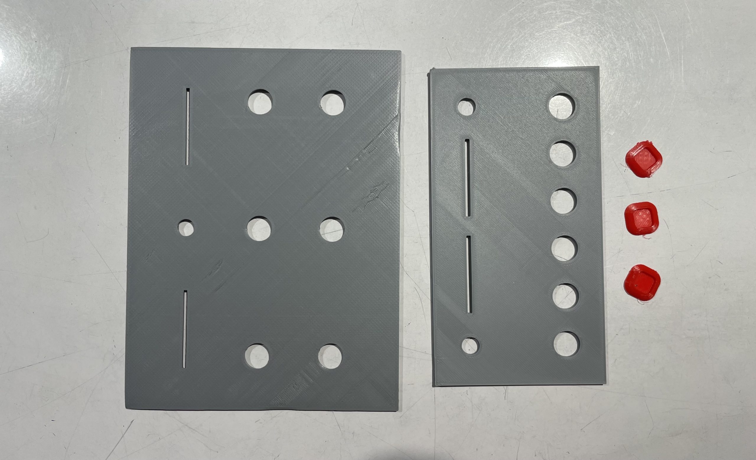 a set of 3D printed objects. two panels with holes for buttons and sliders and then three button caps 