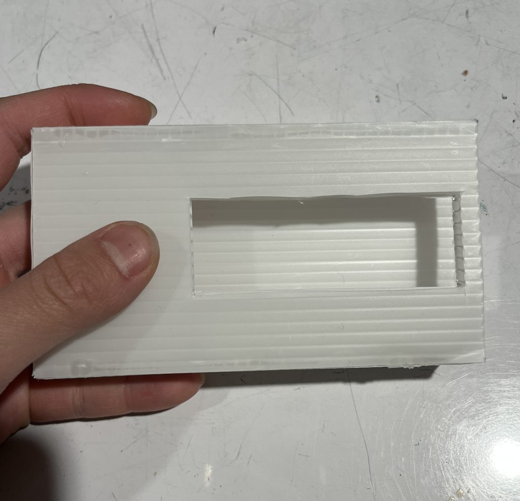 Hand holding white box with a rectangular hole cut into it
