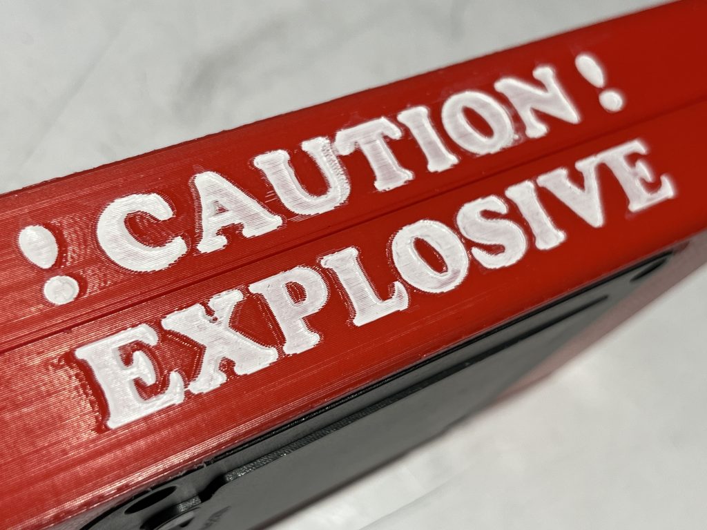 Red box turned to the long side revealing white text that reads "!Caution! Explosive"