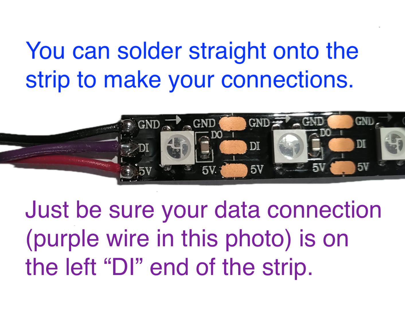 Closeup of left edge of LED strip. Three wires are soldered onto the strip's surface: a black wire is soldered to the top pin labeled "GND," a purple wire is soldered to the middle pin labeled "DI," and a red wire is soldered to the bottom pin labeled "5V." The image includes two sentences: "You can solder straight onto the strip to make your connections. Just be sure your data connection (purple wire in this photo) is on the left 'DI' end of the strip."