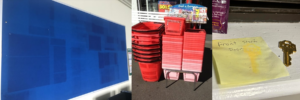 blue paper with dark rectangles faded in, red shopping baskets, a key on a sticky note with imprint